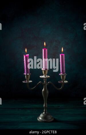 Candle magic. Purple candles in a vintage candleholder on a dark background Stock Photo