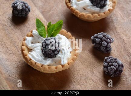 Homemade tartlets with blackberry, whipped cream and mint. Tasty sweet dessert concept Stock Photo