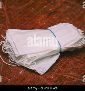 A stack of medical protective masks on a scratched wooden table Stock Photo