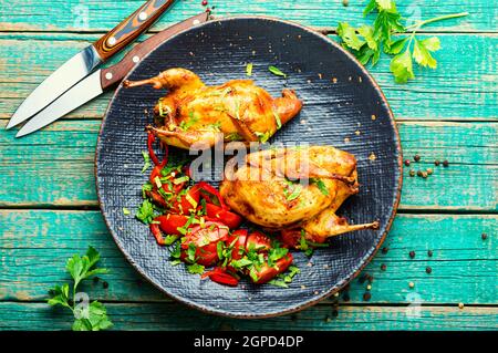 Roasted whole quail and spring vegetable salad.Appetizing baked quail meat Stock Photo