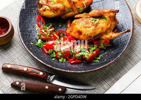 Roasted whole quail and spring vegetable salad.Appetizing baked quail meat Stock Photo