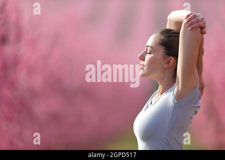 Side view portrait of a relaxed runner stretching arms in a field after run Stock Photo