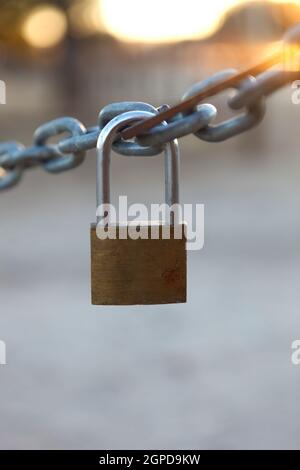 Closed padlock hanging from a thick chain Stock Photo