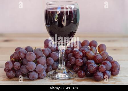 Bowl with grape juice and bunches of fresh grape on wooden surface. Grape juice is rich in several nutrients and can bring many health benefits. Detox Stock Photo