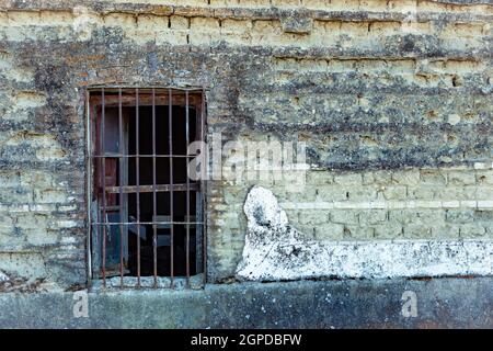 Window with rusty bars on the facade of an old house Stock Photo