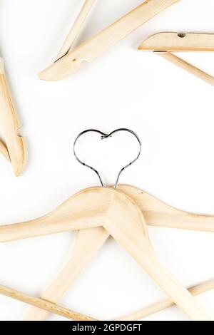 Conscious consumption slow fashion concept. Heart of clothes hangers entwined on white background.  Stock Photo