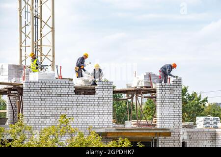Vilnius, Lithuania - September 28 2021: New buildings or houses under construction with workers at work against cloudy sky Stock Photo