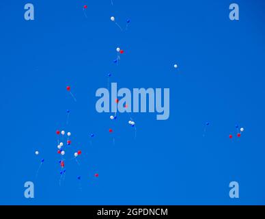Multicolored balls, filled with helium, fly in the blue sky. Stock Photo