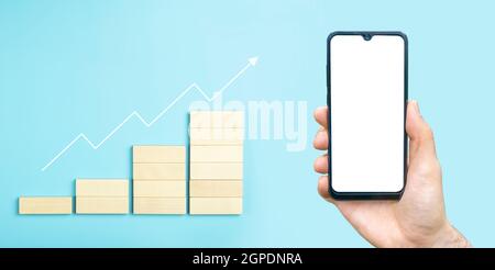 Business growth, development plan concept and business analytics background. Hand with blank smartphone for stock exchange application. High quality photo Stock Photo