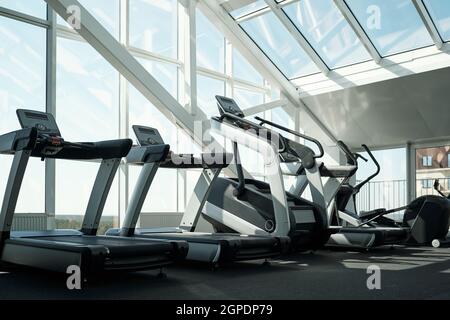 Horizontal no people shot of treadmills and other exercise machines in modern gym with panoramic windows Stock Photo