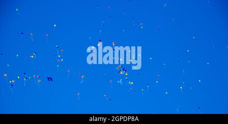 Multicolored balls, filled with helium, fly in the blue sky. Stock Photo