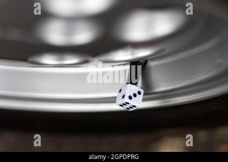 Dice cube alloy wheel valve cap cover. Number three 3 in focus. Classic retro old dust cap rolling a die. Stock Photo