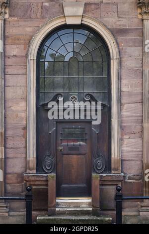 Ancient old solid wooden door on side of historic stone church.  Solid exterior door architecture closed in archway bars over windows high security. Stock Photo