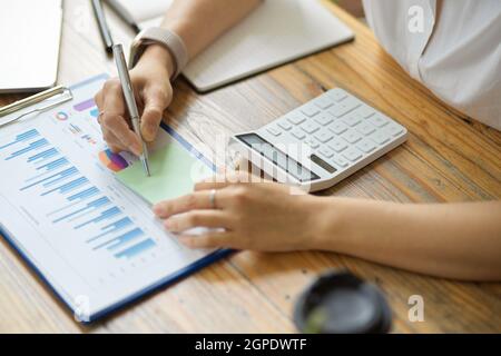 Close-up, An Accountant or business owner writes on sticky notes, takes notes on post notes, works on financial reports, and calculates business budge Stock Photo