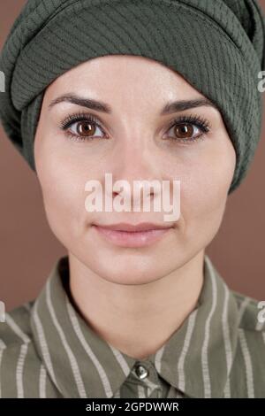 Vertical close-up studio portrait of attractive Muslim woman with beautiful brown eyes wearing turban looking at camera Stock Photo