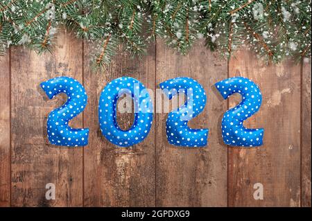 2022 balloon text on wooden rustic table with branches of Christmas trees. Happy New year eve invitation with Christmas blue foil balloons 2022. Happy Stock Photo