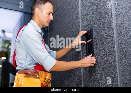 Builder installing an intercom. renovation in a renovated building Stock Photo