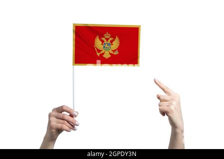 A beautiful female hand holds a Montenegro flag to which she shows the finger of her other hand, isolated on white background. Stock Photo