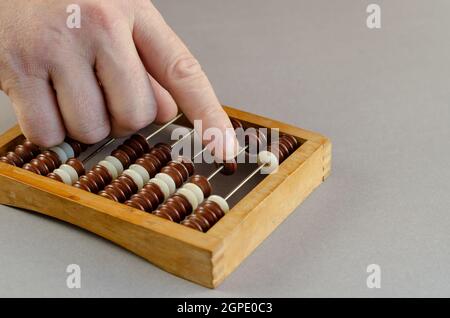 An adult male makes calculations on wooden abacus. The man's han Stock Photo