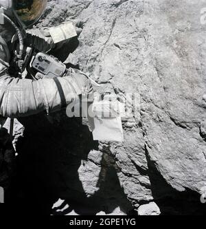 (23 April 1972) --- Astronaut Charles M. Duke Jr., lunar module pilot of the Apollo 16 lunar landing mission, examines closely the surface of a large boulder at North Ray Crater during the third Apollo 16 extravehicular activity (EVA) at the Descartes landing site. This picture was taken by astronaut John W. Young, commander. Note the chest-mounted 70mm Hasselblad camera. Stock Photo