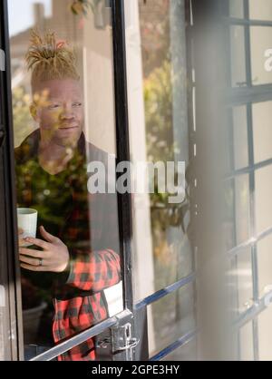 Thoughtful albino african american man with dreadlocks drinking coffee Stock Photo
