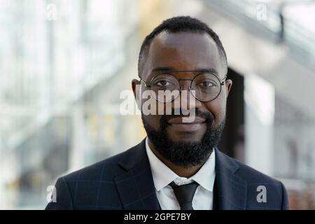 Young smiling man in eyeglasses and elegant suit looking at you in trade center Stock Photo