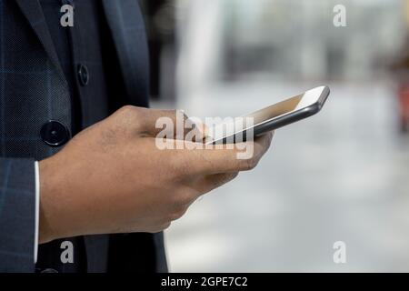 Hand of young African businessman in formalwear scrolling in mobile phone in front of camera Stock Photo