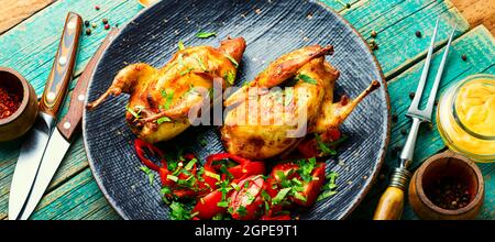 Roasted whole quail and spring vegetable salad.Appetizing baked quail meat Stock Photo