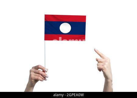 A beautiful female hand holds a Laos flag to which she shows the finger of her other hand, isolated on white background. Stock Photo