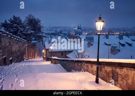 Cityscape of Prague in winter. Snow covered staircase ​against Lesser Town early morning. Stock Photo
