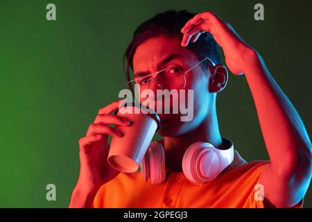 Portrait of young handsome man, student in casual clothes isolated on green vintage studio backgroud. Human emotions concept. Stock Photo