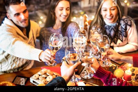 People group celebrating Christmas toasting champagne wine at home dinner party - Winter holiday concept with young friends enjoying time together Stock Photo