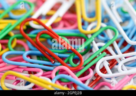 Lots of multi-colored paper clips of same size on table. Stock Photo