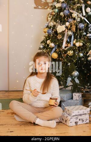 A young girl eat peanut butter on Holiday Christmas background Stock Photo