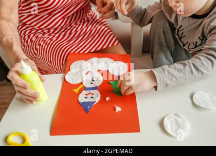 A Little boy with grandmother make Christmas craft, greeting card. Top view. Stock Photo