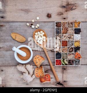 Alternative health care dried various Chinese herbs in wooden box and dried quince ,ginger and lotus seed in wooden spoon with mortar on old wooden ba Stock Photo