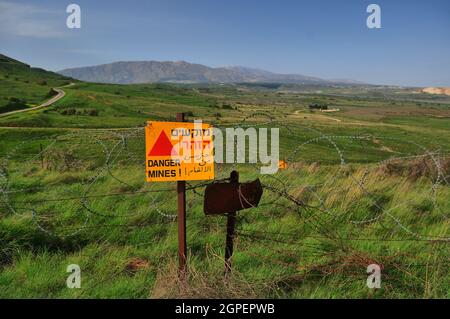 Minefield danger mines yellow warning sign on a barbed wire fence in the Golan Heights, Israel Stock Photo