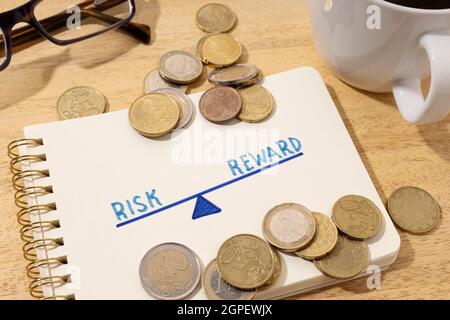 Risk reward concept. Drawing on notepad and coins on desk Stock Photo