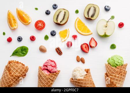 Cones and colorful various fruits raspberry ,blueberry ,strawberry ,orange slice , half kiwi ,apple,tomato and peppermint leaves setup on white backgr Stock Photo