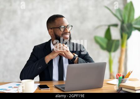 African American man using laptop thinking looking away Stock Photo