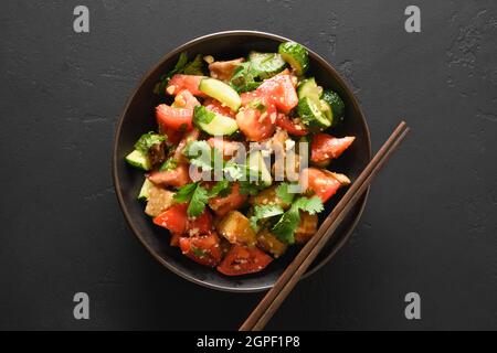 Chinese crispy spicy eggplant with cucumber, garlic, tomatoes, fresh cilantro leaves in oyster sauce and black vinegar on black background. View from Stock Photo