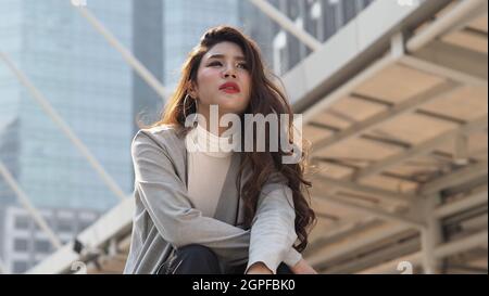 Lay off. Sacked. Fired business woman sitting on stairs of office building outside. Depressed young business woman unemployment due to coronavirus cri Stock Photo