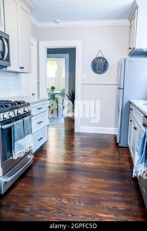 A small cottage kitchen with gray cabinets and dark hardwood floors in a short-term rental house Stock Photo