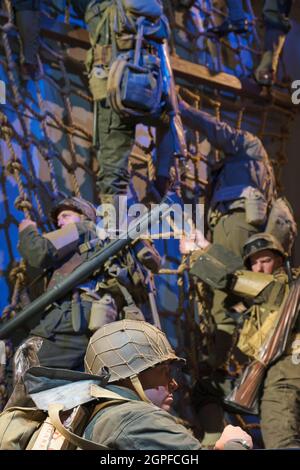Soldiers climbing down a rope ladder onto a Higgins landing craft ...