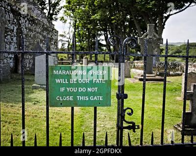 Funny sign on entrance to Kildalton church yard with Kildalton Cross in the background Stock Photo