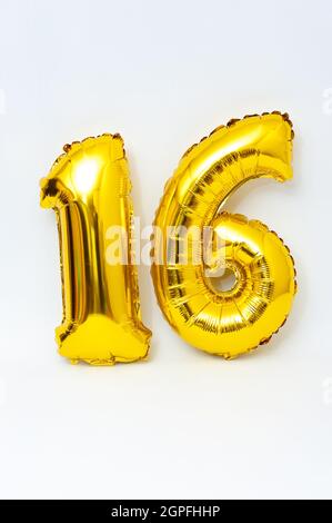 Inflatable numeral 16 sparkling metallic golden color isolated on white background. Close-up. Vertical shot. Stock Photo
