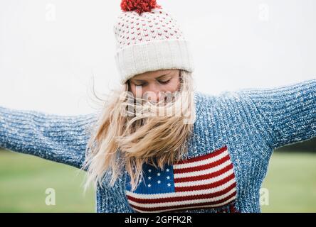 woman wearing an American flag whilst running outside in the rain Stock Photo