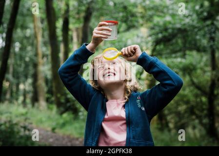 girl looking through a magnifying glass at bugs in the forest Stock Photo