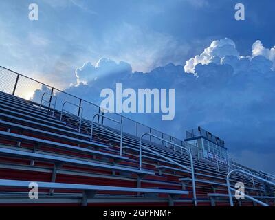 Thunder storm clouds approaching empty stadium stands with a little light still shining through on a summer evening. Stock Photo