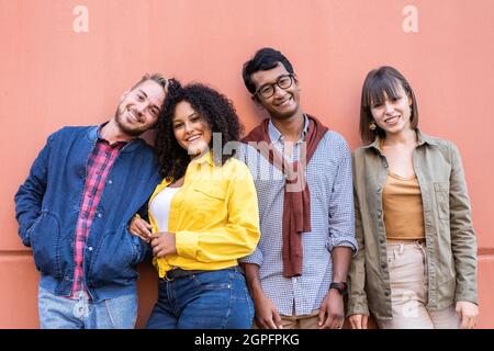 Multiracial friends group having fun at wall on university college campus - Diverse culture students portrait celebrating outside - Young smiling peop Stock Photo